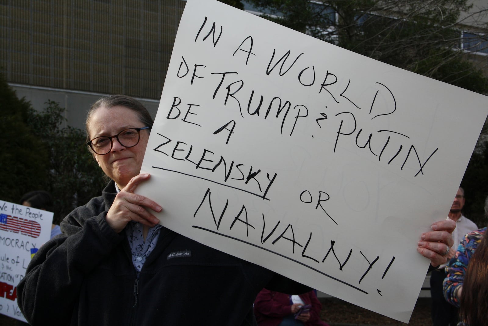 A protester holds a sign outside a town hall holds by Rep. Chuck Edwards in Asheville, N.C. on Thursday, March 13, 2025. (AP Photo/Makiya Seminera)