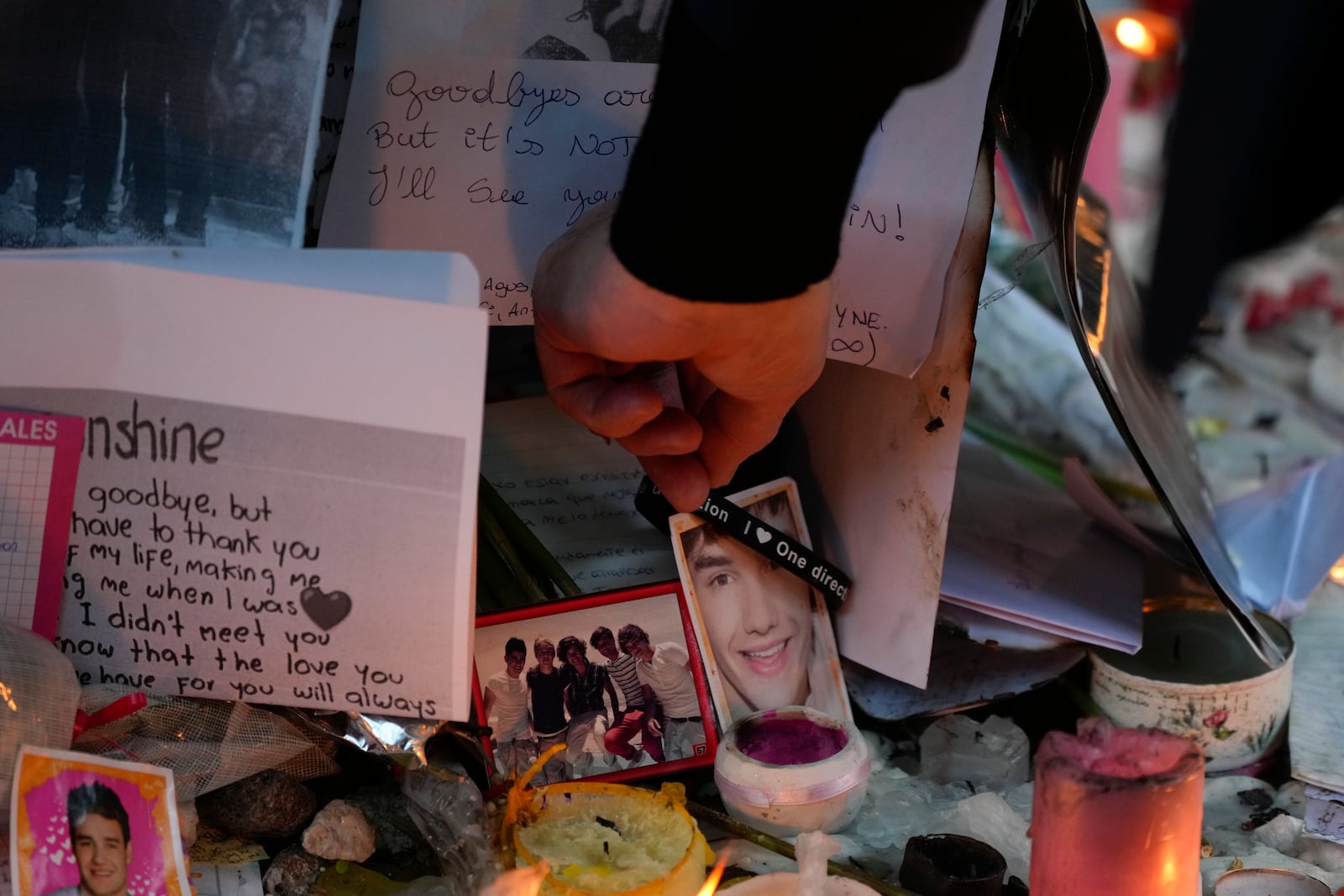 Geoff Payne, the father of former One Direction singer Liam Payne, touches a gel bracelet hanging on a picture of his son while visiting a memorial outside the Casa Sur Hotel where the British pop singer fell to his death from a hotel balcony, in Buenos Aires, Argentina, Friday, Oct. 18, 2024. (AP Photo/Natacha Pisarenko)