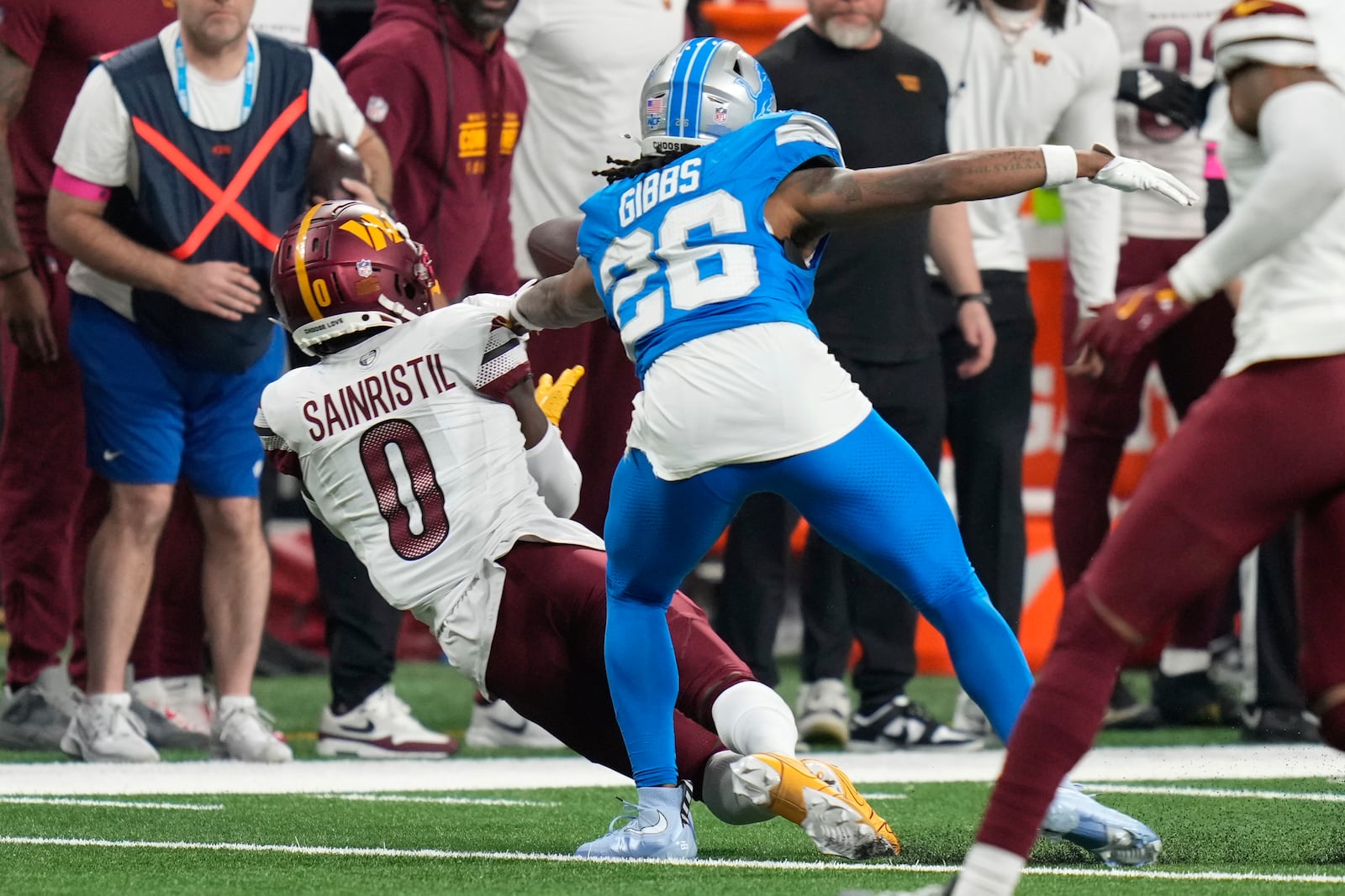 Washington Commanders cornerback Mike Sainristil (0) intercepts a pass intended for Detroit Lions running back Jahmyr Gibbs (26) during the second half of an NFL football divisional playoff game, Saturday, Jan. 18, 2025, in Detroit. (AP Photo/Seth Wenig)