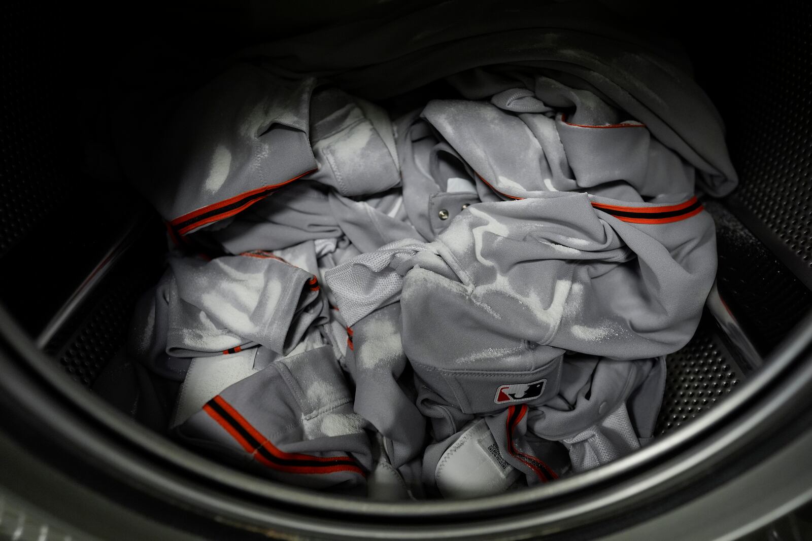 Baseball pants are sprinkled with Water Mark Protein Release Powder in a washing machine during San Francisco Giants baseball spring training at the team's facility, Monday, Feb. 17, 2025, in Scottsdale, Ariz. (AP Photo/Carolyn Kaster)