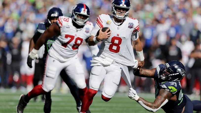 New York Giants quarterback Daniel Jones (8) runs with the football as Seattle Seahawks defensive end Leonard Williams (99) tries to tackle during the first half of an NFL football game, Sunday, Oct. 6, 2024, in Seattle. (AP Photo/John Froschauer)