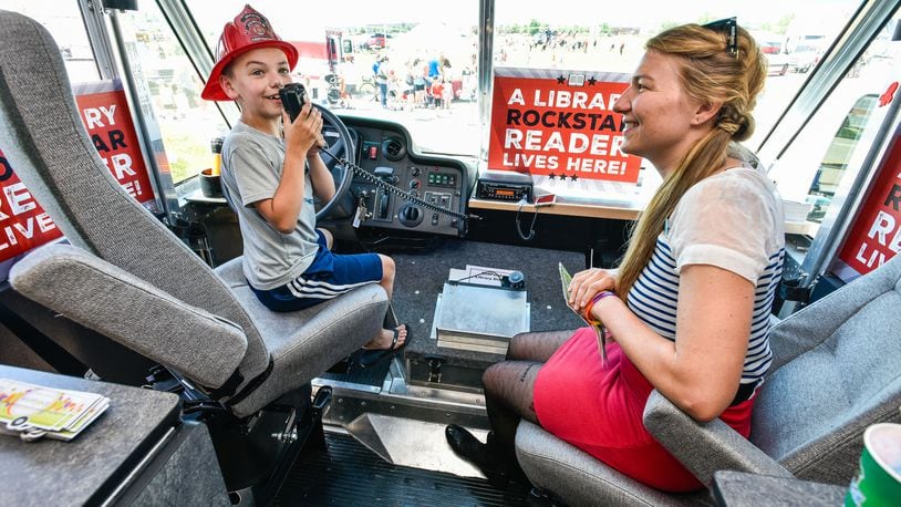 MidPointe Library's Jenn Effinger lets Jack Whitehouse, 8, talk on the speaker inside MidPointe's Library on Wheels during West Chester Township's Touch A Truck event Friday, June 15 at The Square @ Union Centre. Fire trucks, police vehicles, helicopters, lift trucks, snow plows and more were on display for kids to climb in and honk horns during the free event. NICK GRAHAM/STAFF