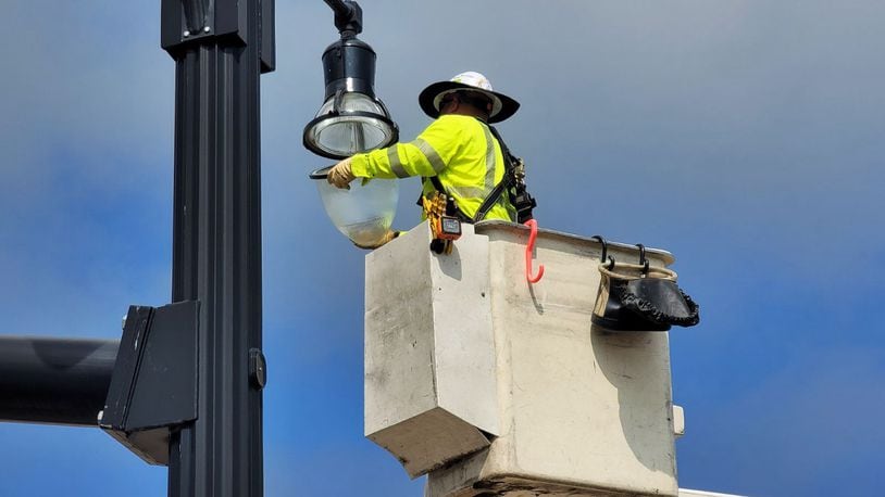 Hamilton utility employee Adam Wong works on a light post on Monday, March 4, 2024, at the intersection of High Street and MLK Jr. Boulevard. Hamilton City Council is considering decreasing electric rates and increasing natural gas rates. NICK GRAHAM/STAFF